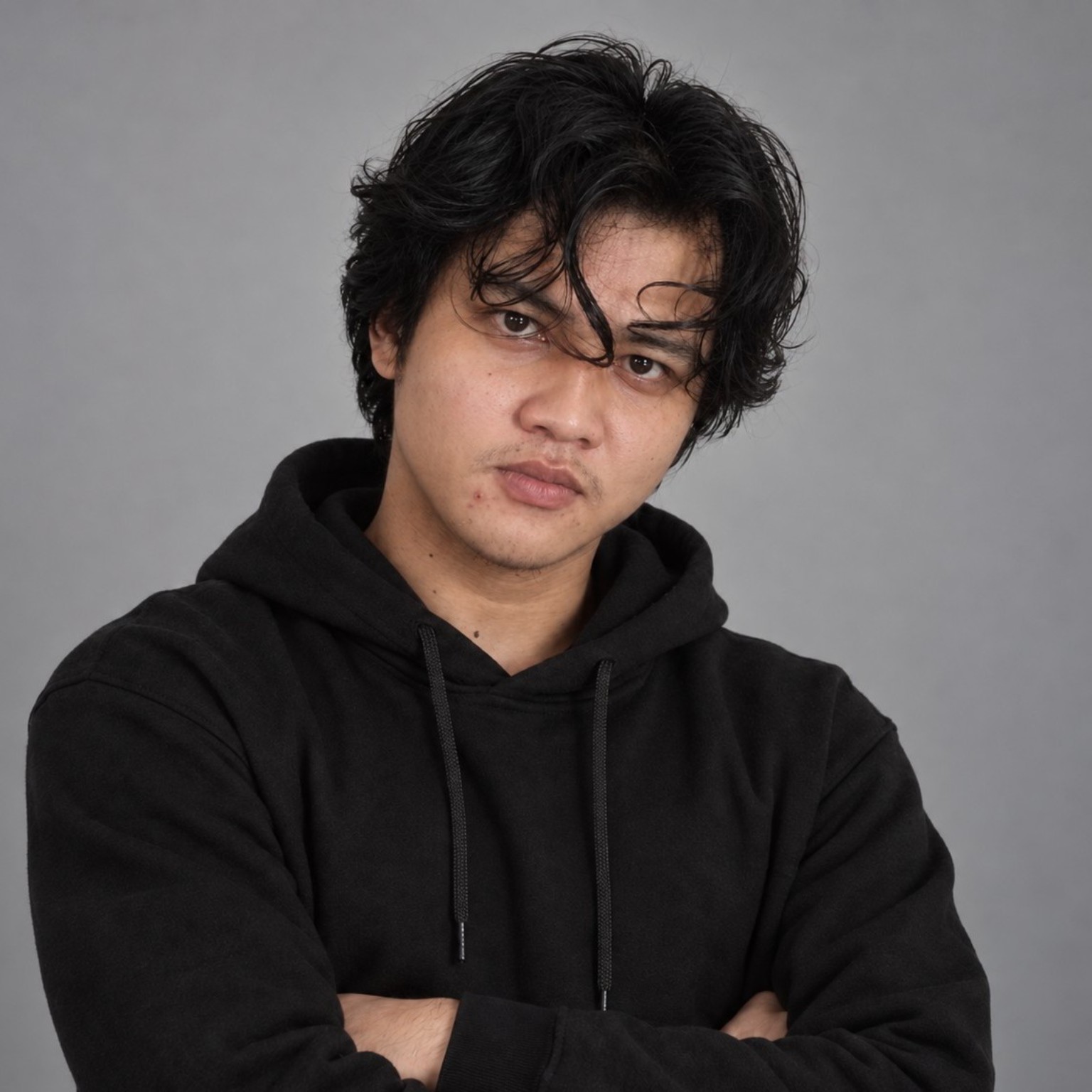 Aziz Nurrochman in a black hoodie, standing with arms folded